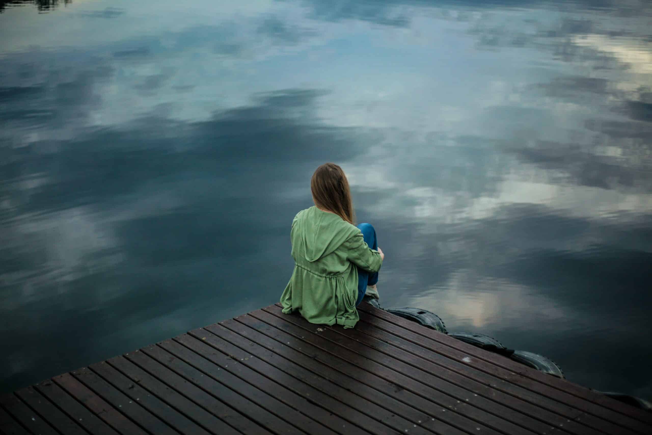 A girl looking at the body of water with a blurred effect.