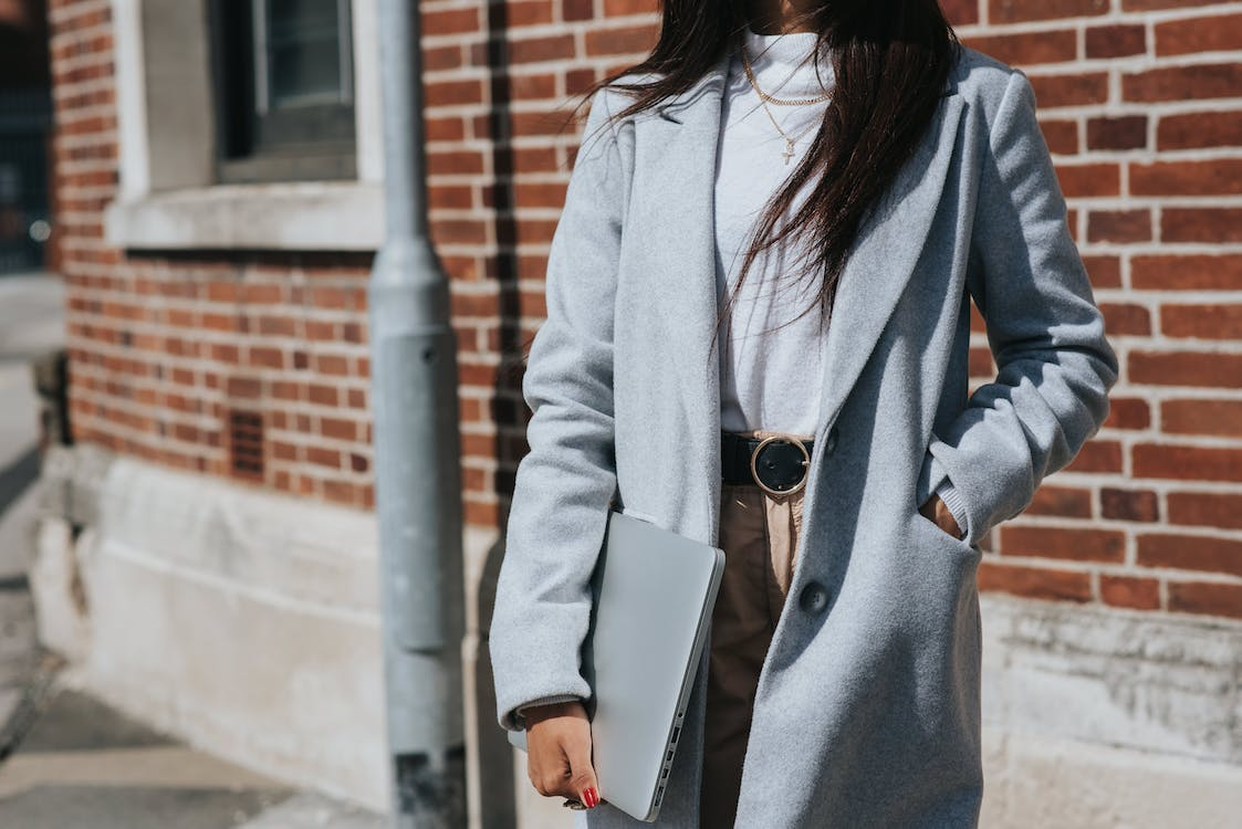 a woman wearing a white blouse, beige pants, black belt and a grey coat what to wear to a job fair