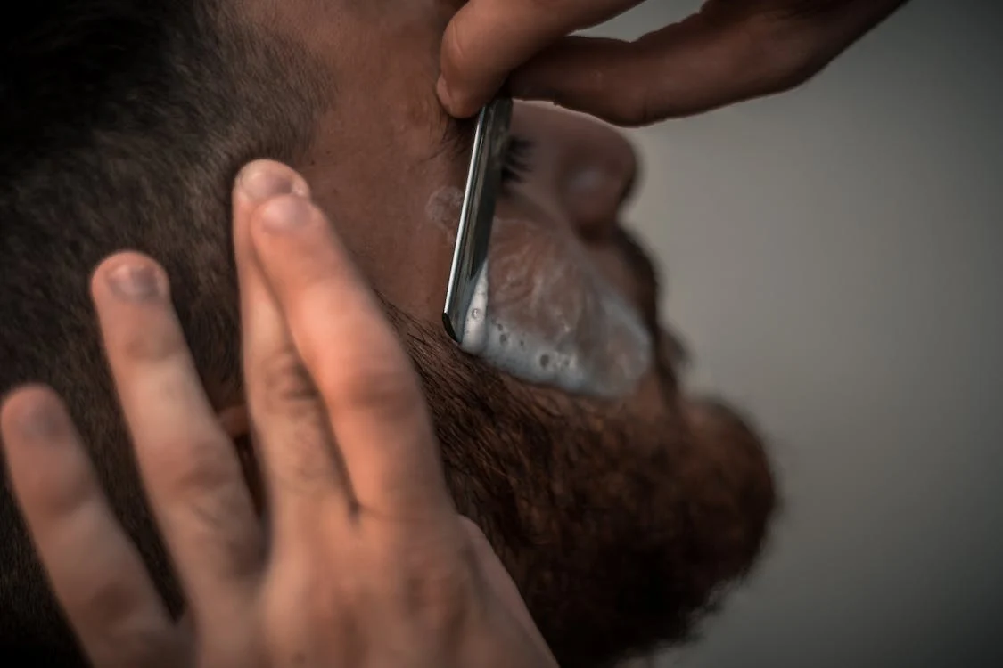 a barber shaving a man's beard